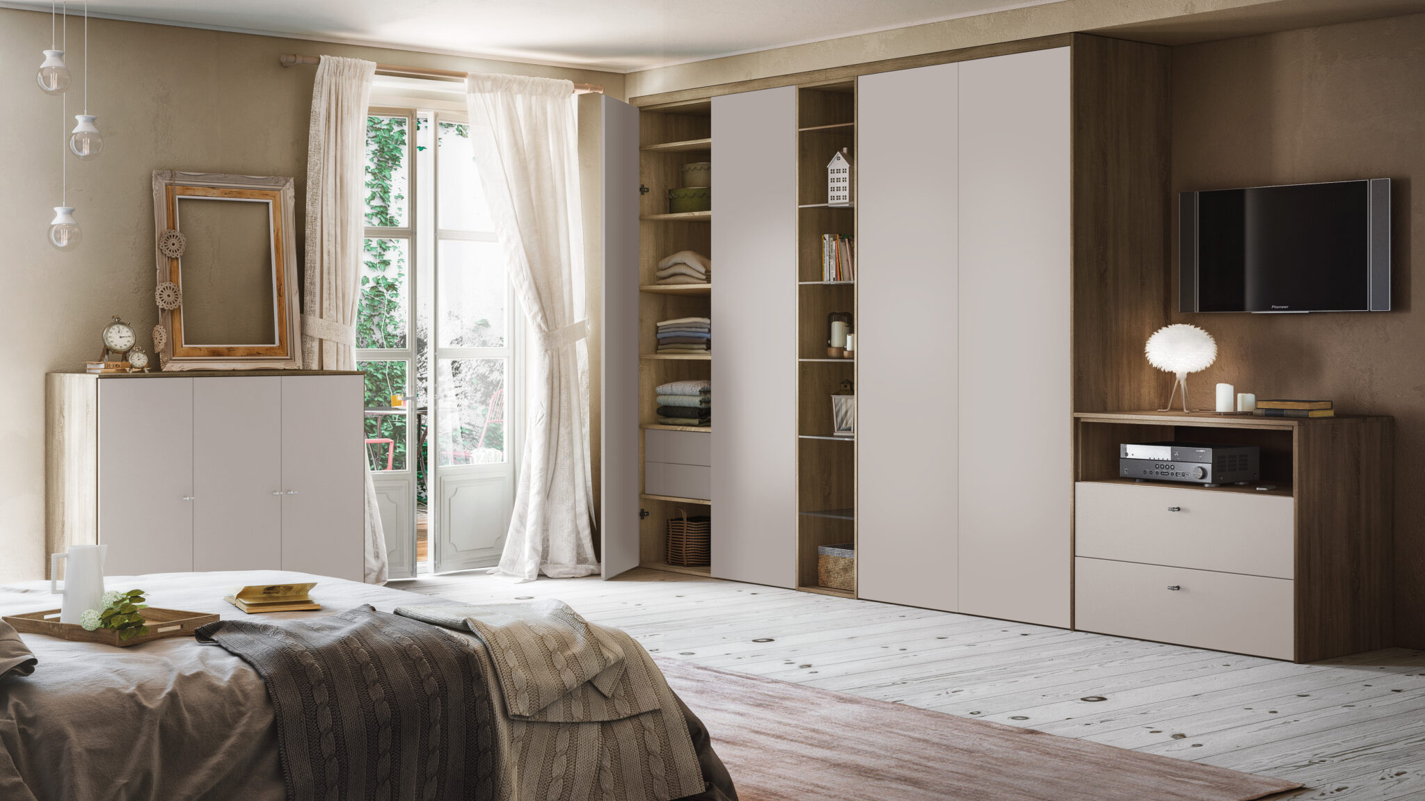 Une chambre avec un lit couvert de plaids, une armoire beige intégrée, et une fenêtre avec rideaux en voile blanc.