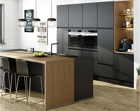 Cuisine moderne avec des armoires noires, un îlot central en bois, des chaises noires et des luminaires suspendus.